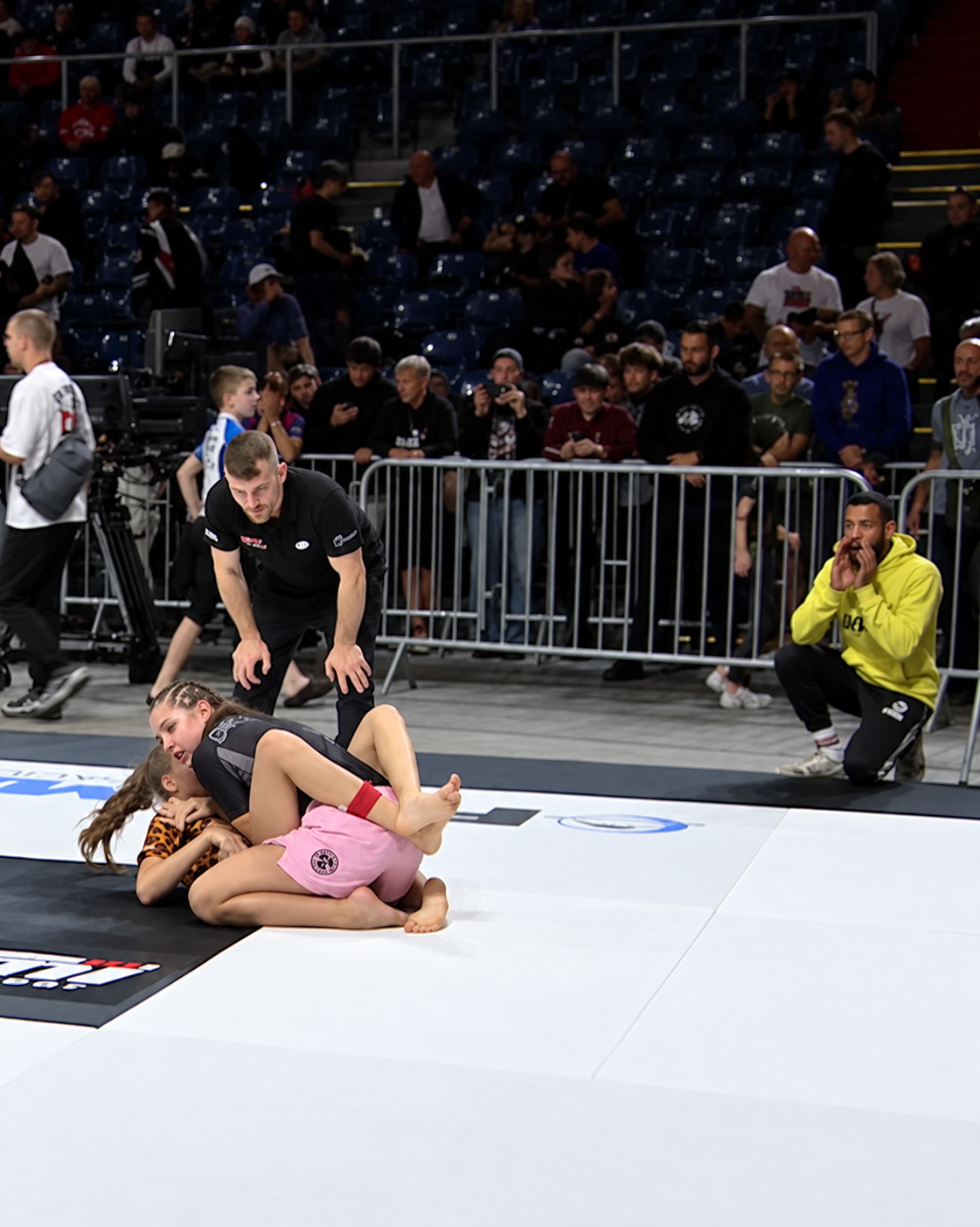 Joleen Bugge von GYMRAY Bamberg im Bodenkampf bei der ADCC Amateur-WM 2026 in Krakau, am Mattenrand coacht Ray im gelben GYMRAY-Hoodie